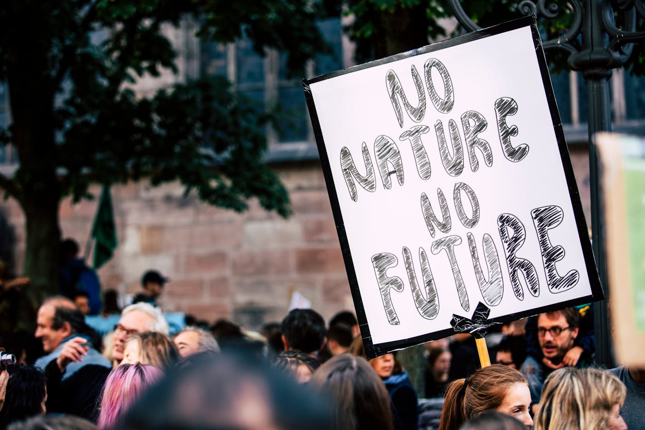 Large group of people rallying with a sign advocating for nature protection and climate action.